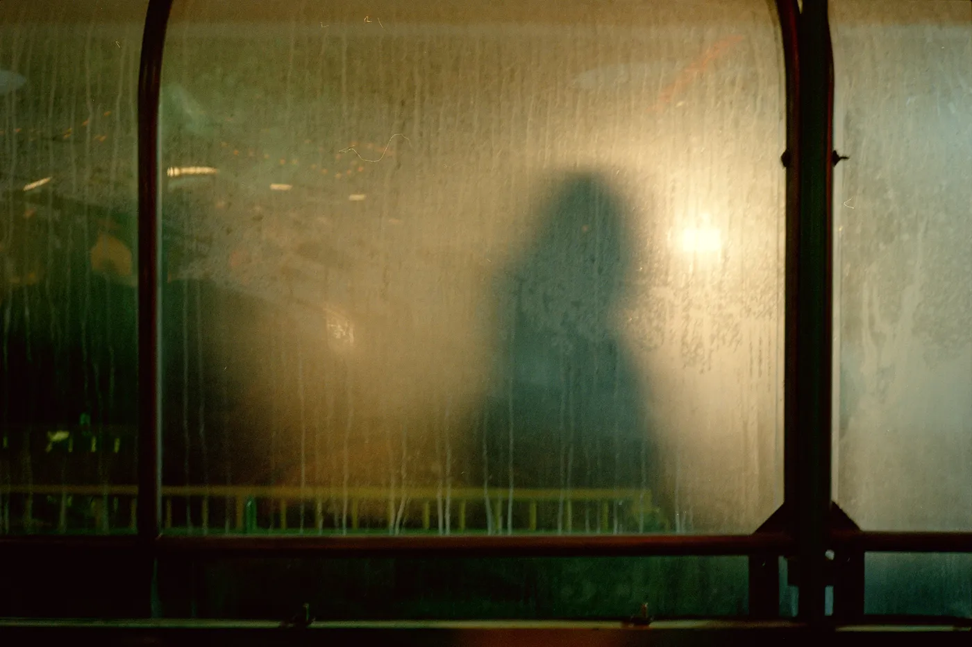 The shadow of a person on frosted glass panels, lit from behind in warm light.