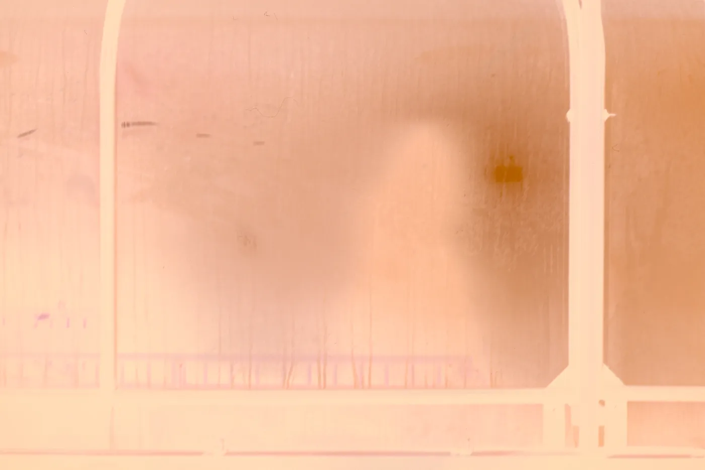 The raw scan of the glass: the panels are dark teal and the shadow a pale shape, under the orange base.