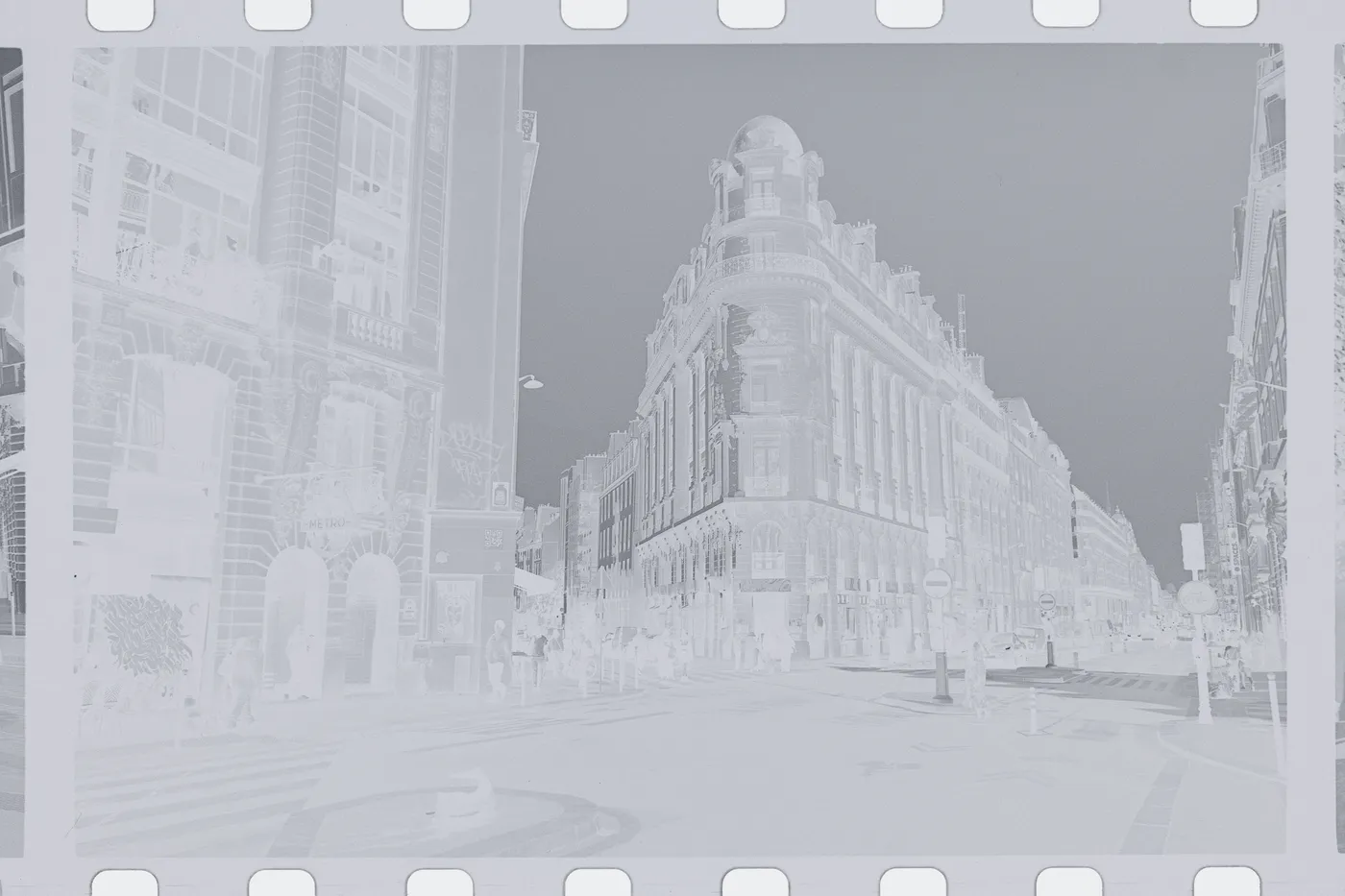 The raw scan of the corner: tones reversed, the bright sky black and the stone dark, sprocket holes clear along the edges of a black and white film.